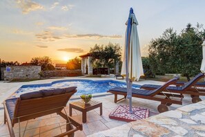 Un espace aménagé au bord de la piscine, avec des chaises longues, un jacuzzi et une pergola.