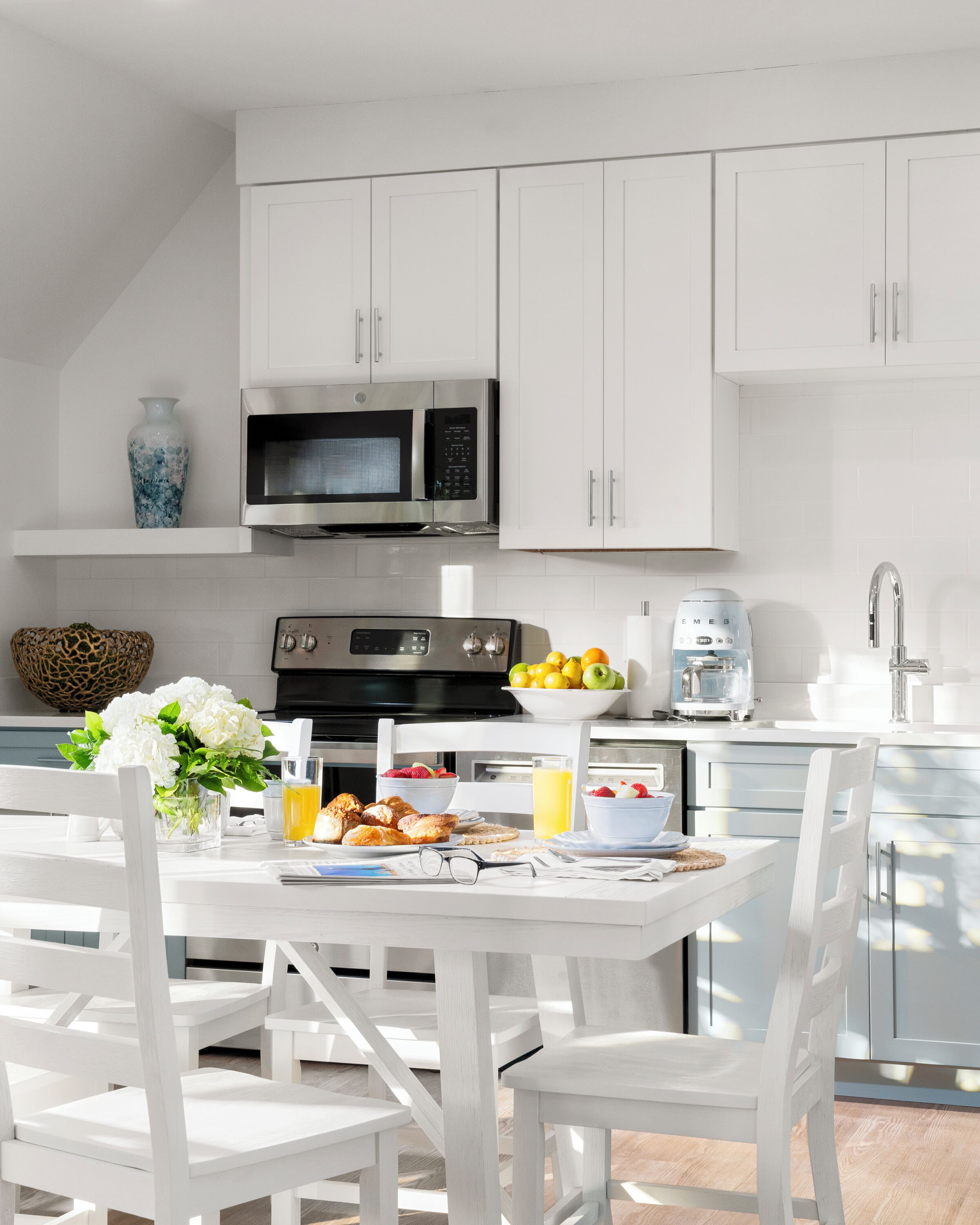A modern kitchen with white cabinetry, a stainless steel microwave, and a coffee maker.