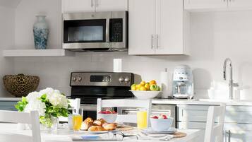 A modern kitchen with white cabinetry, a stainless steel microwave, and a coffee maker.