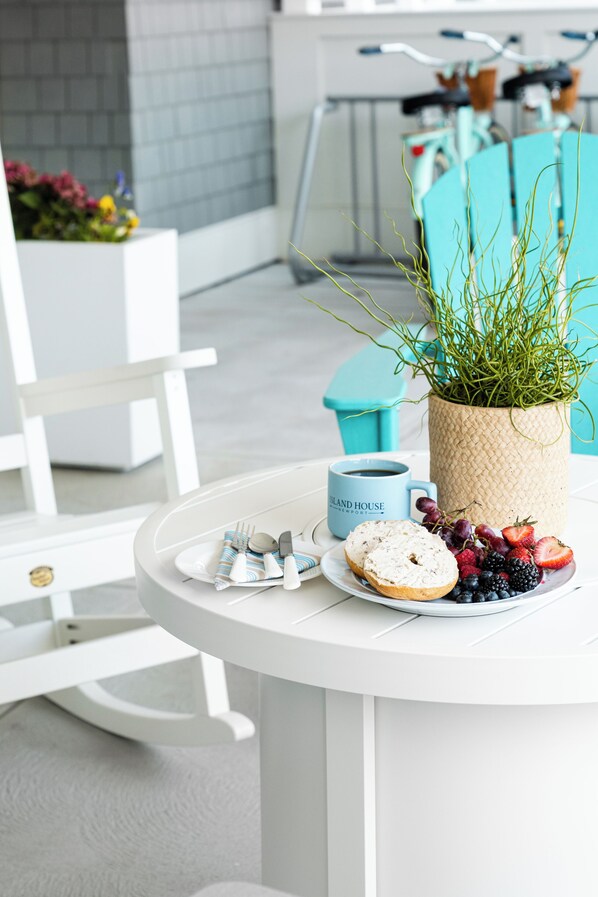 A round white table with a coffee mug, a plate with food, and a potted plant. - Island House Newport (Newport)