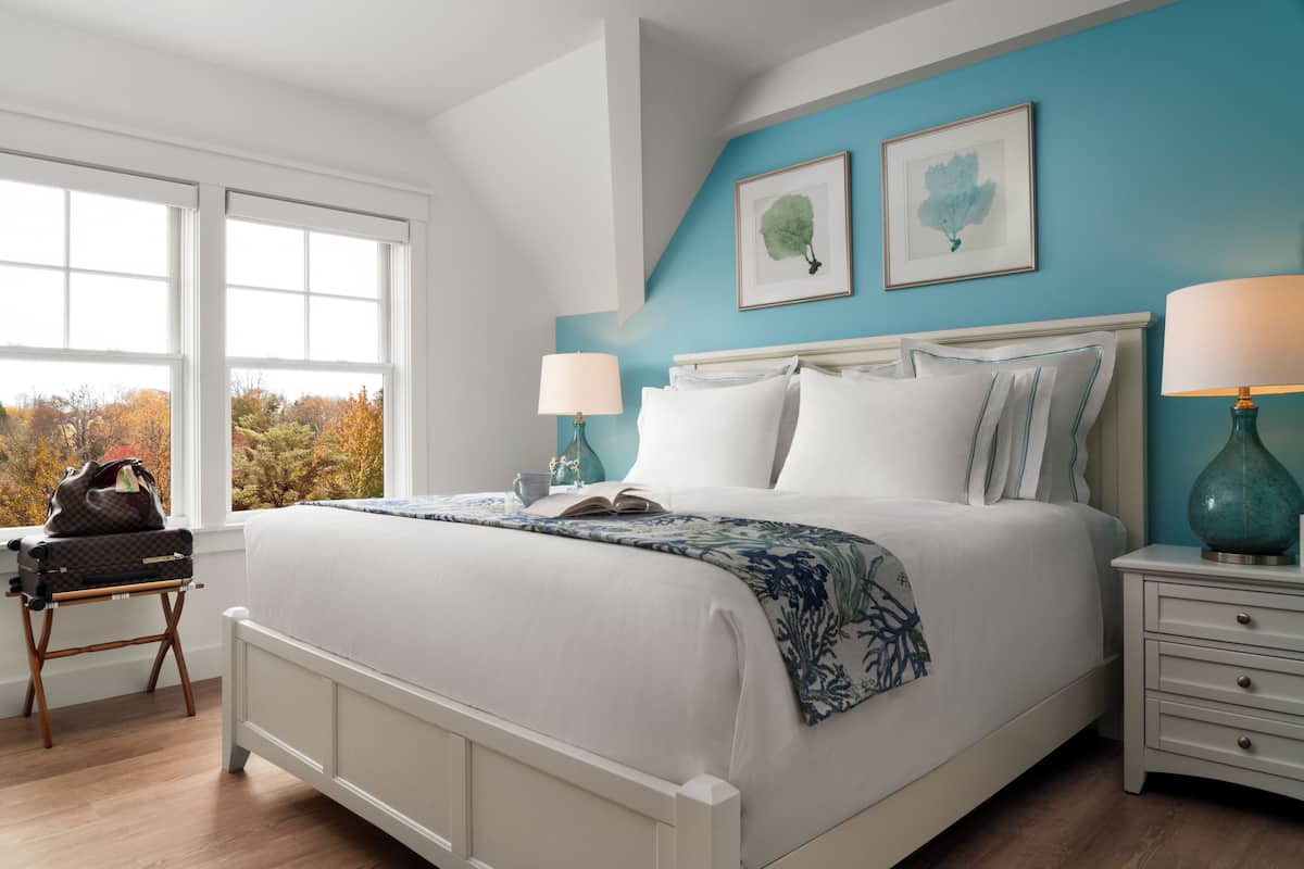 A bedroom with a bed, bedside tables, and a window with a view of trees.