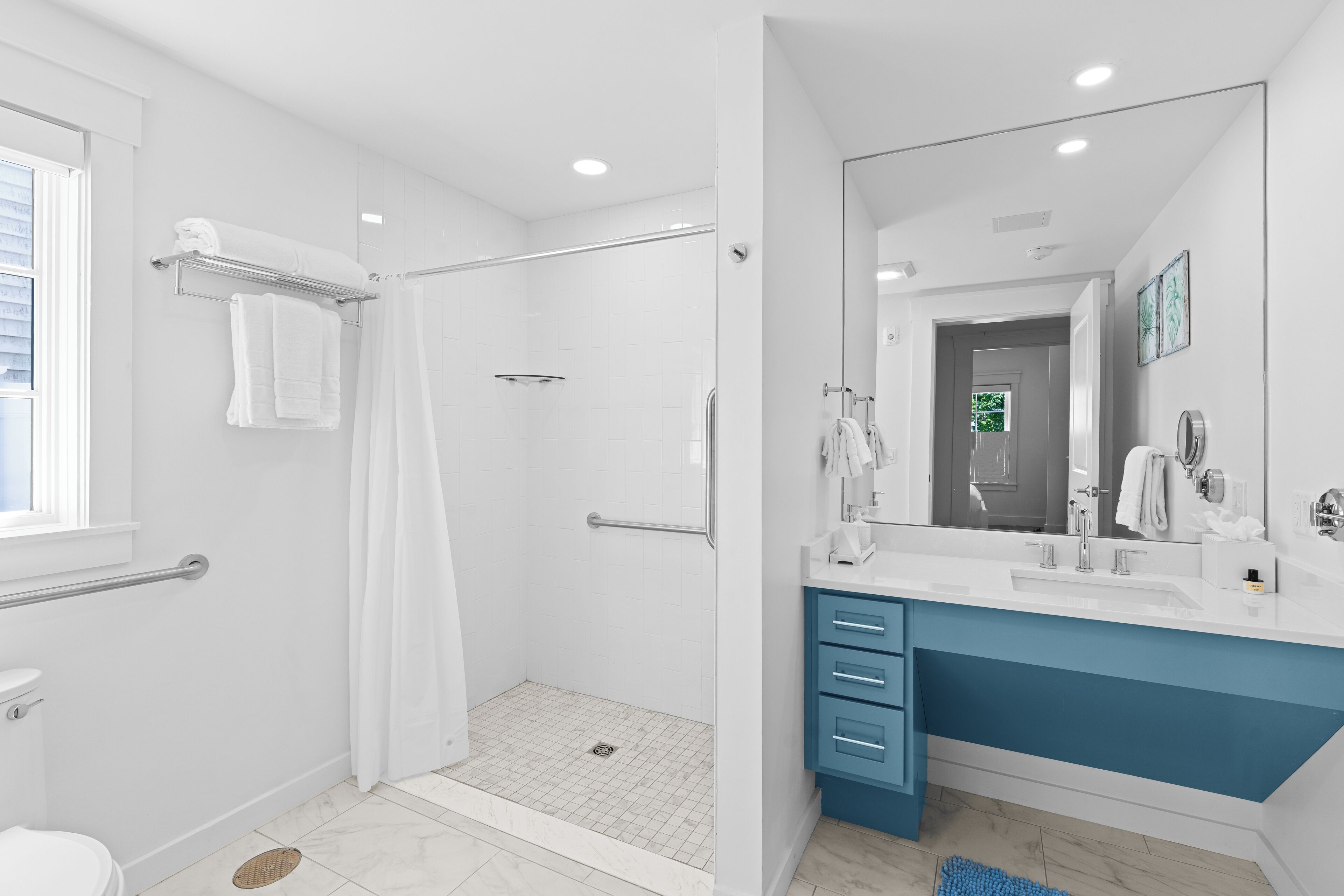 A modern bathroom with a walk-in shower, a toilet, a sink, and a vanity with drawers.
