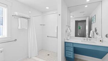 A modern bathroom with a walk-in shower, a toilet, a sink, and a vanity with drawers.