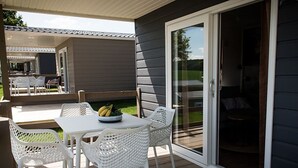 A covered patio with a table and chairs, a sliding glass door, and a view of the backyard. - Compact Chalet in Gulpen With Terrace (Gulpen)