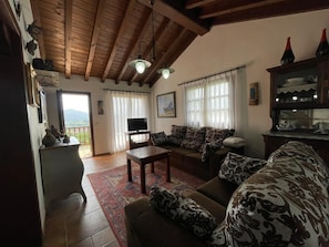 A living room with a sofa, a coffee table, a TV, and a view of the outdoors.
