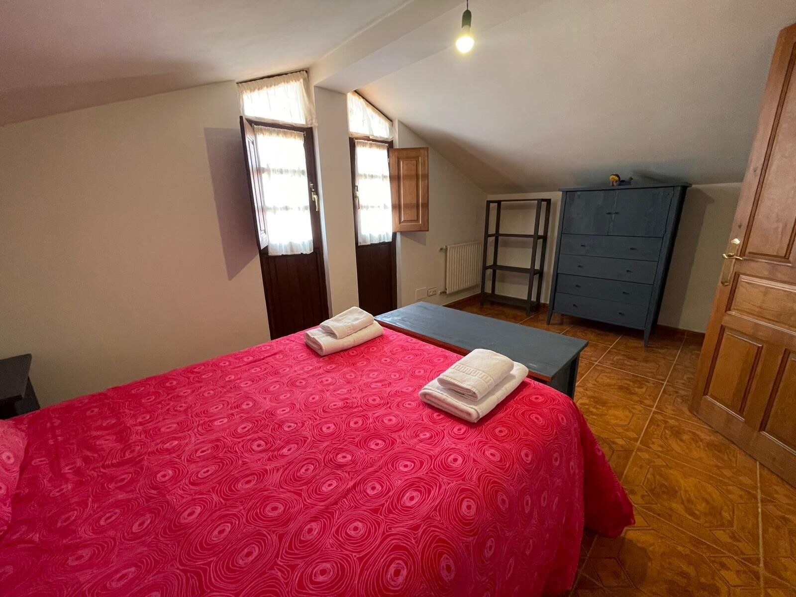 A small, well-lit room with a bed, a desk, and a wardrobe.