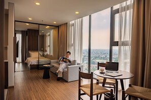 Una habitación de hotel moderna con una cama grande, un sofá, una mesa de comedor y una computadora portátil.