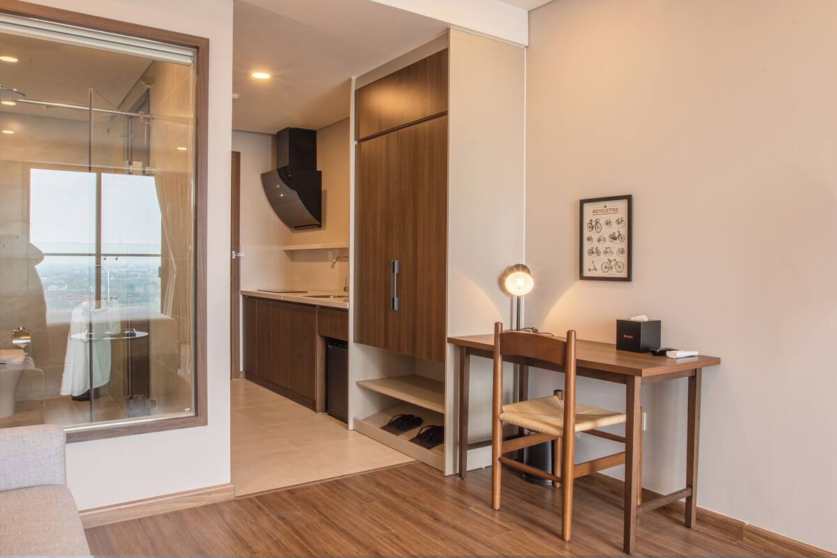 A modern kitchen with wooden cabinets, a built-in oven, and a dining area with a table and chair.