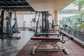 A gym with various exercise equipment, large windows, and a checkered floor. - Mandala Hotel & Suites Hai Duong (Tan Hung Ward, Hai Phong City)