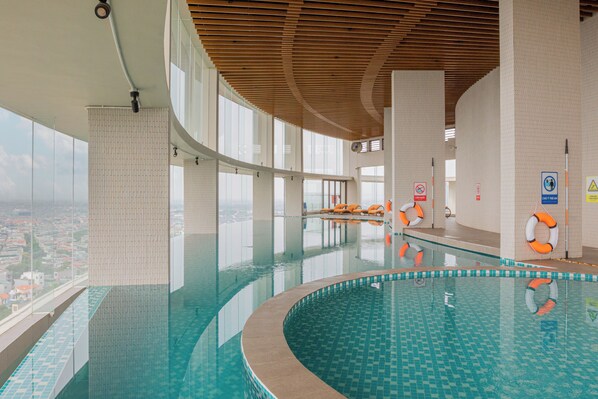 Una piscina interior con vistas despejadas de la ciudad, paredes de azulejos y equipo de seguridad.
