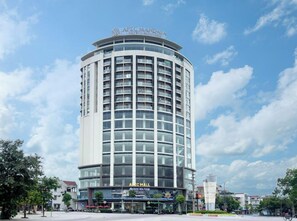 A modern hotel with a curved facade, multiple balconies, and a prominent sign at the top. - Mandala Hotel & Suites Hai Duong (Hai Phong Municipality)