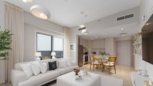 A modern living room with a white sofa, a dining table, and a kitchen in the background.