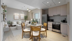 A modern kitchen with a dining area, featuring a round table with chairs, a refrigerator, and a microwave.