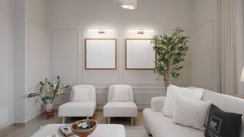 Un salon moderne avec un canapé blanc, deux fauteuils blancs, une table basse et une plante décorative.
