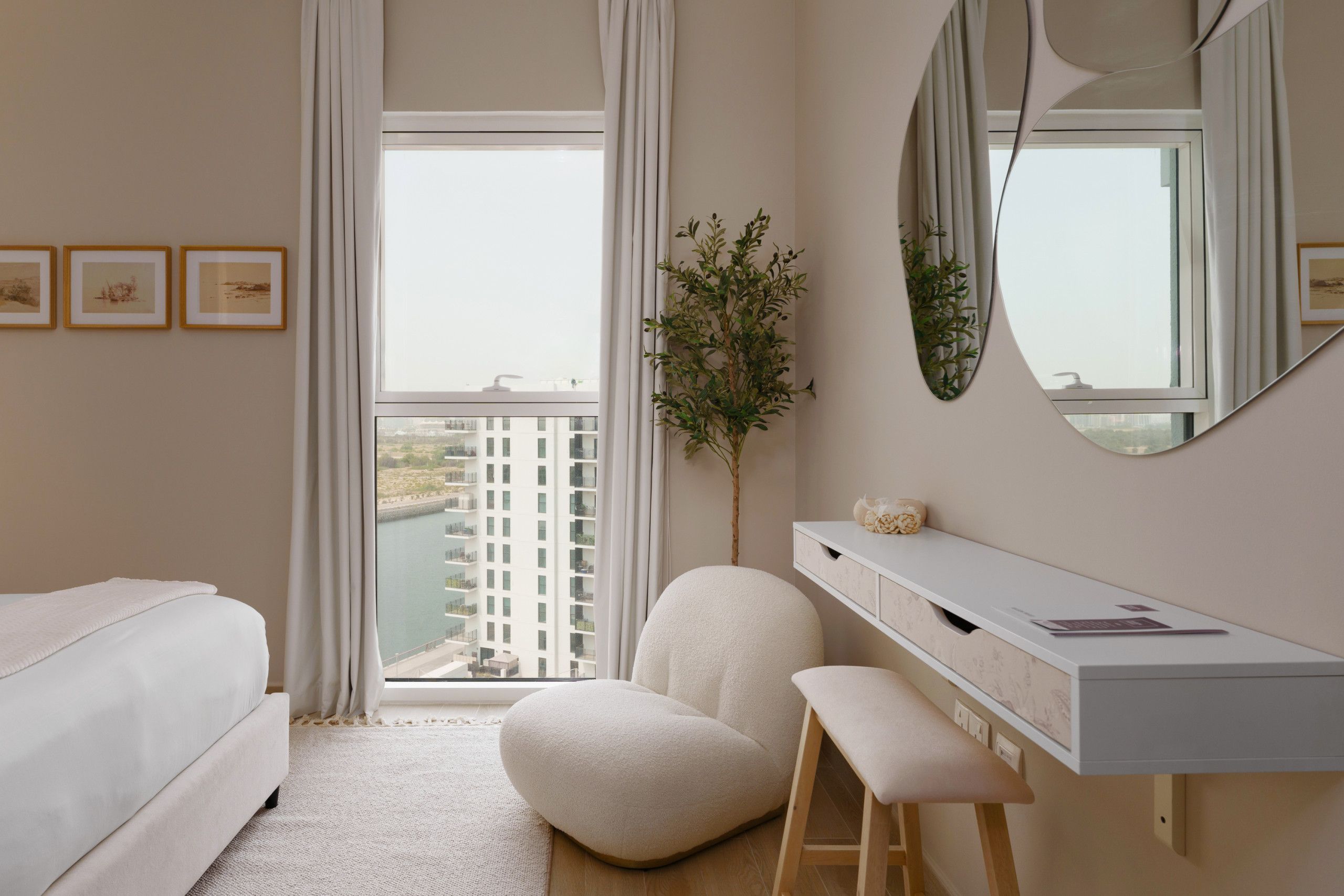 Une chambre d’hôtel moderne équipée d’un lit, d’un bureau, d’une chaise et d’une grande fenêtre donnant sur un immeuble.