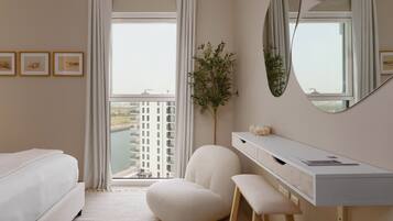 Une chambre d’hôtel moderne équipée d’un lit, d’un bureau, d’une chaise et d’une grande fenêtre donnant sur un immeuble.