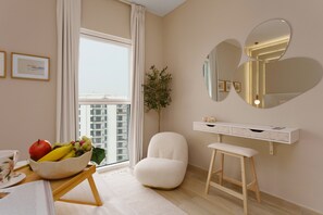 A modern bedroom with a large window, a white chair, a bedside table, and a mirror.