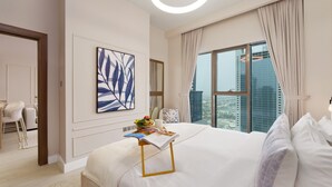 A modern hotel room with a large bed, a dining area with a chair, a table, and a view of the cityscape through the window. - Modern Living w/ Premium Amenities close to Marina (Dubai)