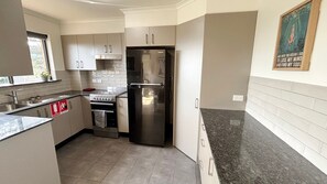 A compact kitchen with a stainless steel refrigerator, a stove, and a sink.
