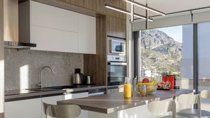 Eine moderne Küche mit einer zentralen Kochinsel, Edelstahlgeräten und Blick auf eine gebirgige Landschaft.
