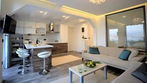 Un salon moderne comprenant un canapé, une table basse et un coin cuisine avec un bar.