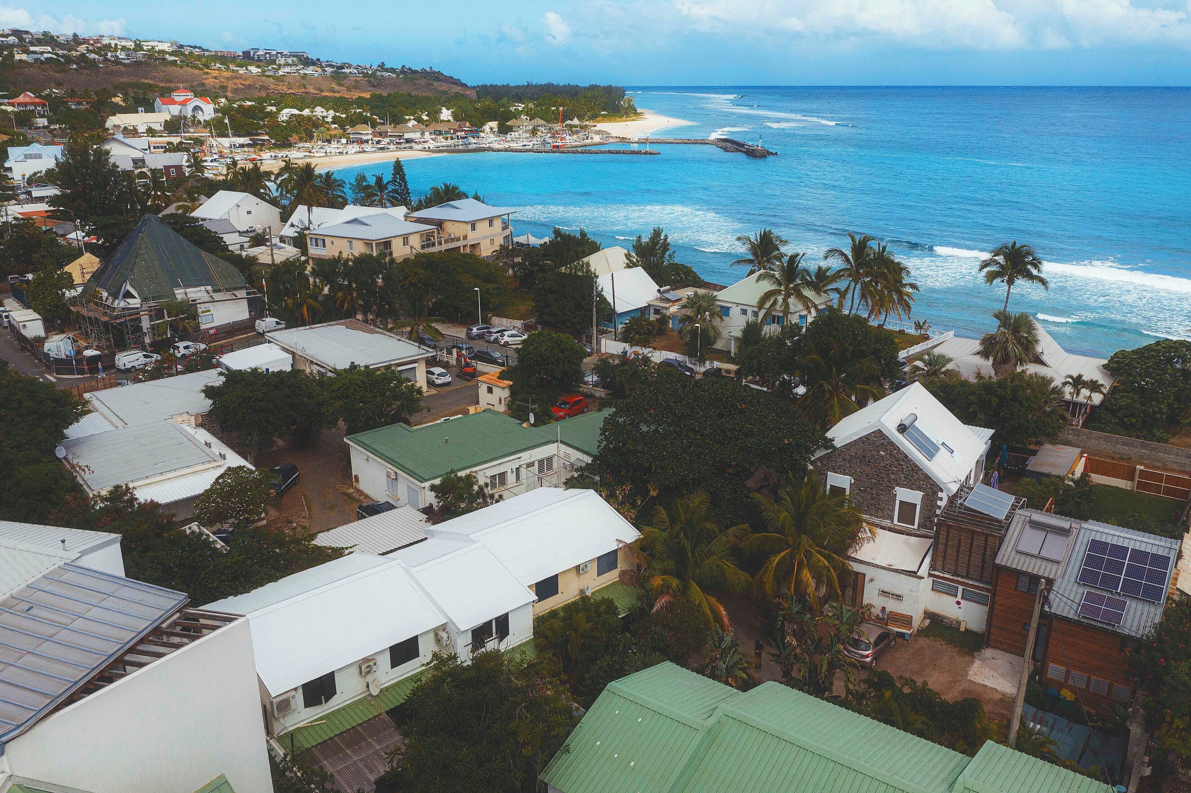A coastal town with residential buildings, a beach, and a pier.