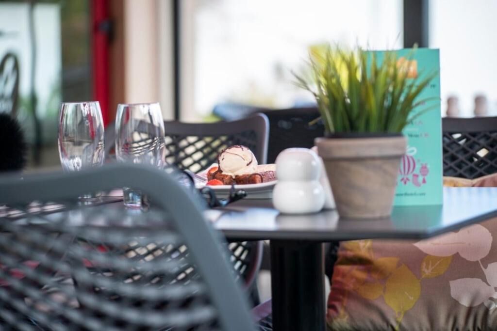 Una mesa con un menú, una planta en maceta y un plato de comida.