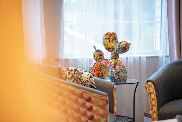 A room with a sofa and armchairs, a small table with decorative items, and a window with sheer curtains. - Emmet Hotel (Clonakilty)