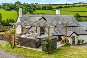 A cozy outdoor patio with a pergola, wicker furniture, and a small garden area.