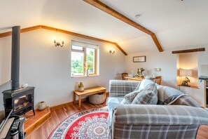 Une pièce chaleureuse avec une cheminée, une table à manger, un canapé et une fenêtre donnant sur un paysage verdoyant.