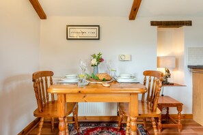 A dining table with chairs, a clock, and a framed sign on the wall. - 1 Bed in Bideford (oc-s29702) (Bideford)