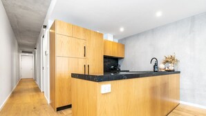 Une cuisine moderne avec des meubles en bois, un plan de travail noir et une cuisinière intégrée.