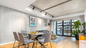 Une salle de réunion moderne, dotée d’une table en verre, de chaises grises et d’une grande fenêtre donnant sur un immeuble.