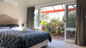 Ein Schlafzimmer mit einem großen Bett und einer Glastür, die zu einem Außenbereich mit Tisch und Stühlen führt.