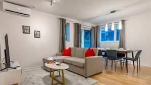 Een moderne woonkamer met een bank, een klein rond tafeltje en een eethoek met stoelen.