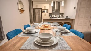 Een eetruimte met een houten tafel voor zes personen, omringd door blauwe stoelen.