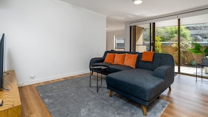 Een moderne woonkamer met een modulaire bank, een klein zwart bijzettafeltje en een grijze vloerkleed.