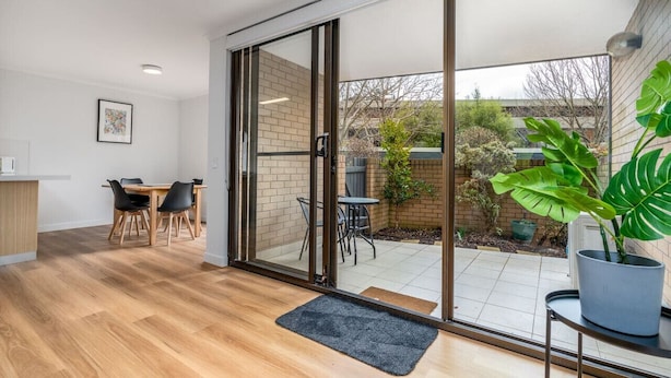Een modern interieur met een eethoek, schuiframen naar een terras en een kamerplant.