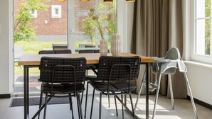 Een eetgedeelte met een houten tafel, zwarte stoelen en hanglampen.