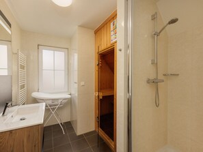 Een badkamer met een wastafel, spiegel en douche.