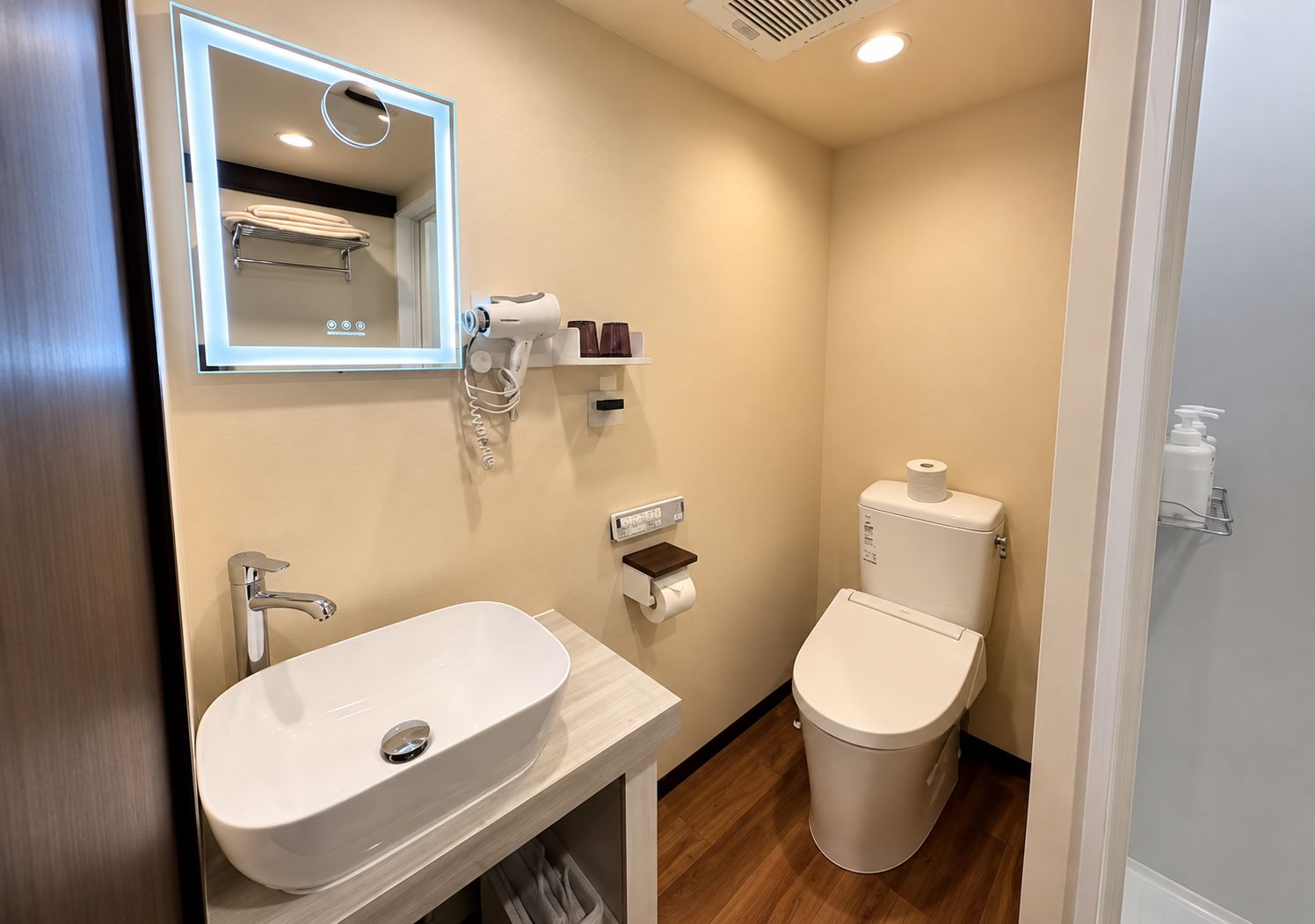 Une salle de bain avec un lavabo blanc, des toilettes et un miroir.