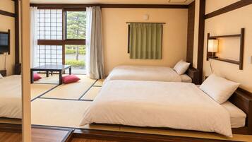 A hotel room with two beds, a window with a view, a table, and a bench.