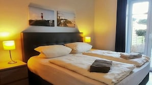 Camera d'albergo con un letto grande, due lampade ai comodini e opere d'arte sulla testiera.