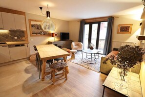 Uma cozinha moderna com uma mesa e cadeiras de madeira, uma área de refeições com uma mesa redonda, um sofá e uma grande janela com cortinas.