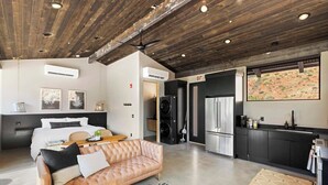 Un interior moderno con un sofá de cuero, una zona de comedor, una kitchenette y una cama.