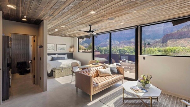 Un intérieur moderne avec un plafond en bois, un canapé, un lit et de grandes fenêtres donnant sur un canyon.