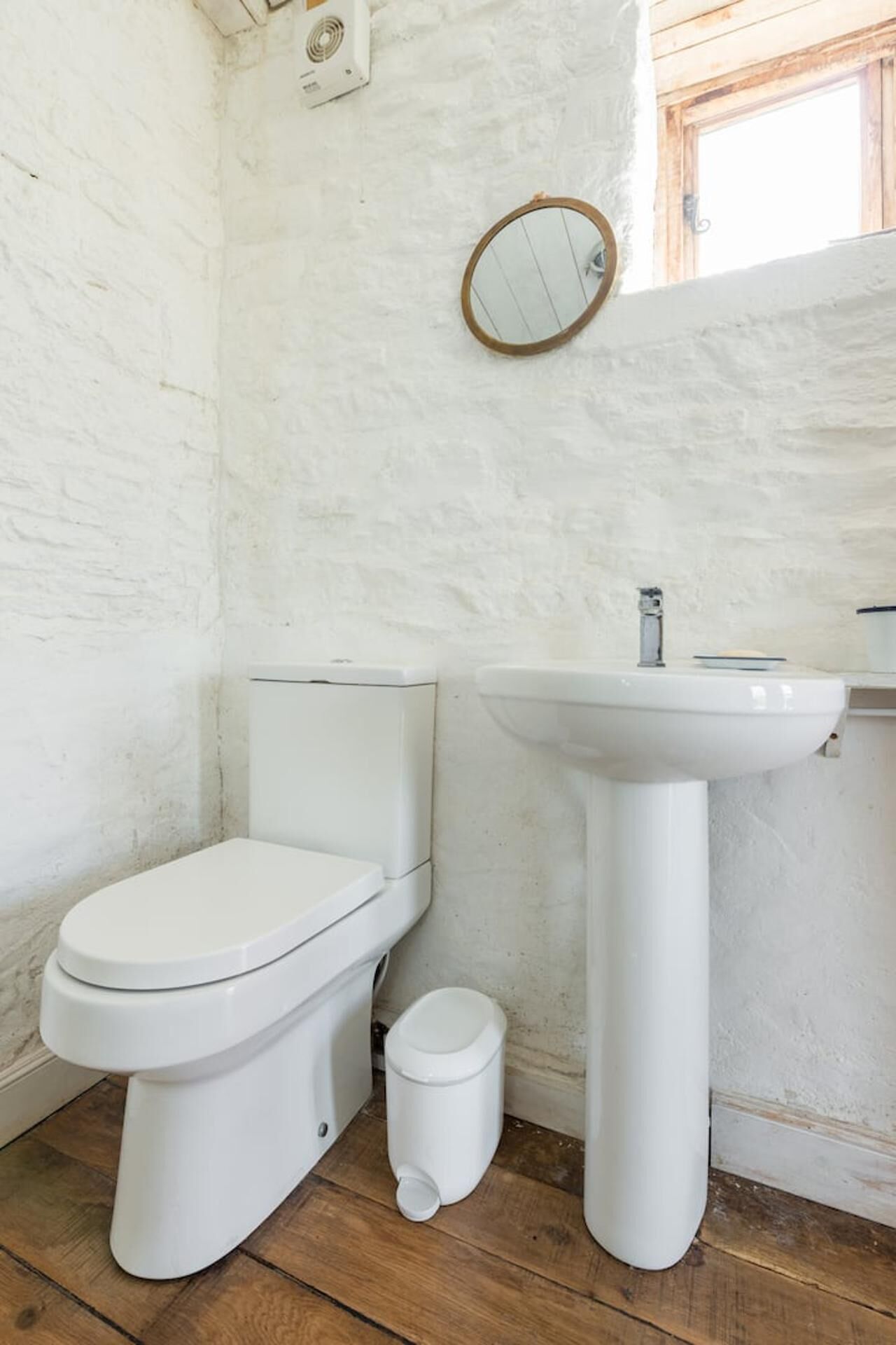 A small bathroom with a toilet, sink, and a mirror.