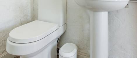 A small bathroom with a toilet, sink, and a mirror.
