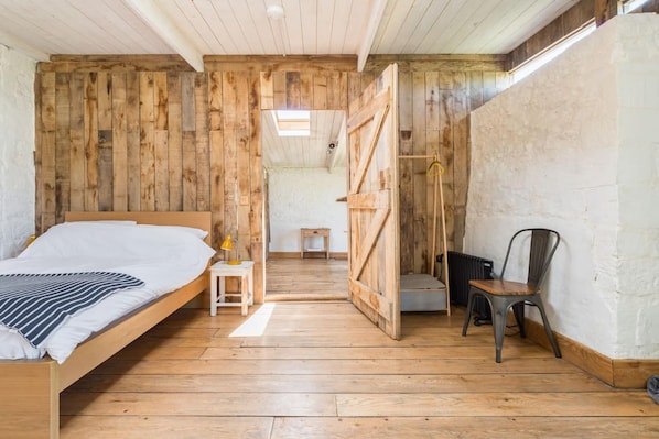 A rustic wooden room with a bed, a small table, and a chair. - Cozy Studio at Crackstone Barns in Minchinhampton (Stroud)