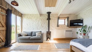Um quarto acolhedor com parede de pedra, um sofá, uma cama, lareira e televisão.